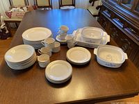 Full set of dishes including plates, cups, saucers, and Corningware casserole dishes with lids.