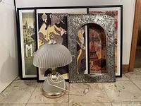 Overall photo showing the three framed posters, decorative metal frame, and lamp on floor