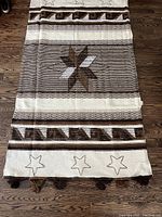 Full view of the rug laid flat on wooden floor, showing star patterns and borders clearly.