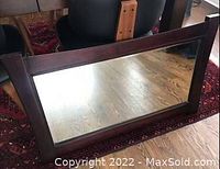 Full view of the large rectangular mirror showing the solid wood frame and reflective glass.
