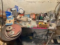 Overview of assorted tool parts and consumables on a wooden table against a wall.