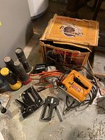 All items grouped: 3 flashlights, 2 staplers, orange electric hand drill, and orange electric angle grinder with cord in original box.