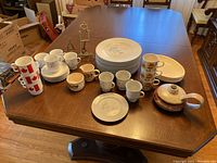 Overall view of all items on table including the plates, cups, candle holder, and teapot.