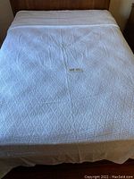 Full view of white bedspread spread over a double/queen size bed to show coverage and pattern.