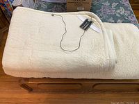 Folded cream-colored merino wool blanket on a wooden surface, showing thickness and texture.