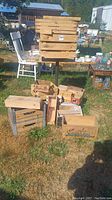 Full view of a collection of wooden boxes including crates and smaller boxes placed on grass outdoors