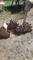 Photo showing two wooden multi-chamber bird houses, each with 8 chambers, and the single-chamber bird house mounted on a post in outdoor setting.
