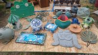 Overview shot showing multiple frog figurines and garden ornaments arranged on wooden surface.