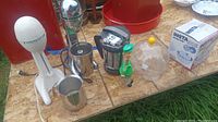 Lot of kitchen items on wooden board including two Hamilton Beach mixers, Insta Egg box, coffee percolator, red mixing bowl, clear dome cover, bobblehead figure.