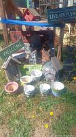 Lot including various bird houses, ceramic planters, wooden signs, and metal plate holder on grass outdoors