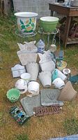 Full lot showing various cast iron plant stands, ceramic and metal pots, and garden decorative items on grass outside.