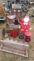 Full set of wooden yard art pieces displayed outdoors on grass including girl figurine, birdhouses, pots and sign.