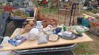 Photo shows various decorative items on a table including shells, trinket box, sea shell soap dish, decorative rock, and a clear vase shaped like a skull.