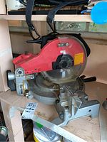 Front and side views of the Craftsman miter saw showing red motor housing, blade, and metallic base with angle scale.