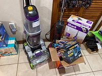 Photo showing Shark steam mop with box, Workzone detail sander box, Ewbank floor scrubber, Bissell carpet cleaner, and box of plastic hangers.