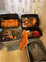 Five storage bins filled with assorted Halloween decorations including orange carved pumpkin lights and hanging ornaments
