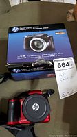 Front view of red HP Digital Camera d3500 with lens cap and original blue box