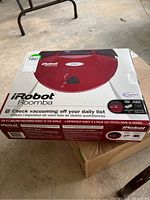 Boxed iRobot Roomba robotic vacuum in red with original product and branding markings.