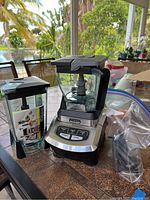Ninja blender base unit with one clear blender container and second container next to it, placed on brown tile surface.