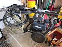 Full view of pressure washer unit mounted on rolling cart with hoses wrapped around the frame and attached spray wand.