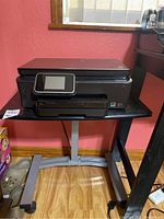 Overall view of the black wood table with metal legs and an HP Photosmart 6520 printer placed on top, showing the size and condition of both items.
