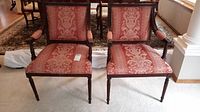 Front view of two mahogany side chairs with coral damask upholstery and carved wood frames, showing the design and condition