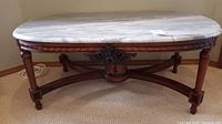 Front view of oval marble-top coffee table on mahogany base