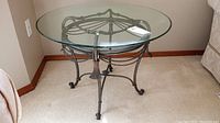 Metal and glass round side table in corner of room, showing full table and base design.