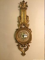 Full frontal view of the carved giltwood wall barometer with visible thermometer at top and barometer dial in center, showing overall condition and size.