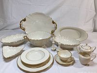 Overall arrangement of dinner plates, salad plates, cups and saucers, bread plates, soup bowls, large platter with handles, matching serving bowl, scalloped bowls, oval platter, sugar bowl, creamer, salt and pepper shakers