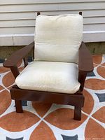 Front view of the brown painted Morris chair with off-white padded cushions.