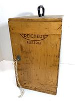 Wooden case closed, showing Reichert Austria stamp and metal latch with string tied.
