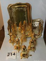 Full view of three pairs of gold plated salt and pepper shakers with two rectangular trays behind them, showing size and arrangement.