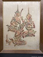 Framed rubbing depicting three traditional Thai figures in ceremonial attire on rice paper, in wooden frame.