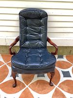 Front view of chair showing full tufted leather upholstery and wooden arms
