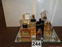 Overall view of 10 vintage perfume bottles arranged on mirrored tray showing bottle shapes, sizes, and cap details