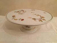 Top view showing the porcelain cake stand with floral and botanical patterns and gold trim.