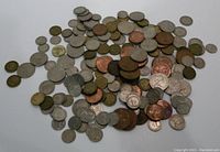 Pile of mixed UK coins in various denominations and metals, shown scattered on white background.
