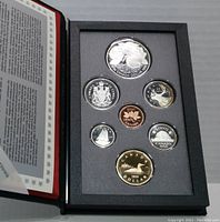 Coins arranged in a fitted black display case with protective clear cover, showing the obverse and reverse sides of the coins.