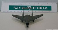 Front view of die-cast model airplane showing twin-boom tail, black nose cone, and landing wheels with a ruler for scale.