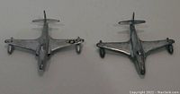 Two silver metal model airplanes from Dinky Toys, Shooting Star design, showing top front view with one plane featuring a U.S. star insignia on the wing.