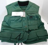 Front view of the green fishing vest showing multiple pockets and a D-ring accessory holder; tags still attached