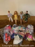 Four dolls and numerous bags of clothing and accessories displayed on a surface