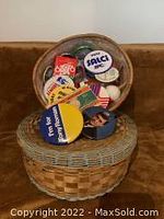 Two woven baskets; one deeper basket filled with assorted buttons and promotional pins placed on top of a larger woven basket with gray accents.