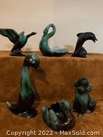 Six Blue Mountain Pottery animal figurines including birds and a frog, arranged on a brown fabric surface