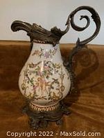 Side view of Chinese crackled porcelain ewer with floral design, brass handle and spout visible.