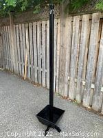 Full view of the tall black vintage coat rack showing entire structure and base basket.