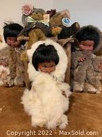 Three Inuit dolls with fur-like clothing and two Bearington bears dressed in vintage clothing with tags attached.