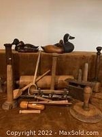 Photo of carved and painted wooden duck decoys along with assorted wooden kitchen tools and utensils on a brown surface.
