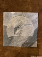 Front of marble carving showing circular carved hunter scene and artist signature.